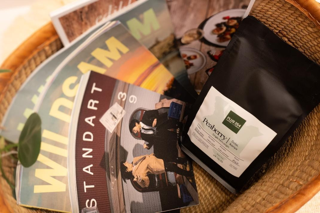 Basket with magazines and a peaberry coffee package on a wooden surface